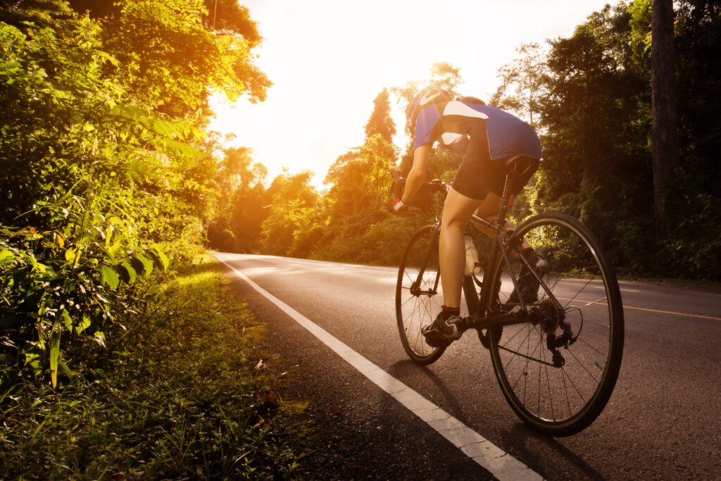 A triathlete on a bike riding towards the sunrise