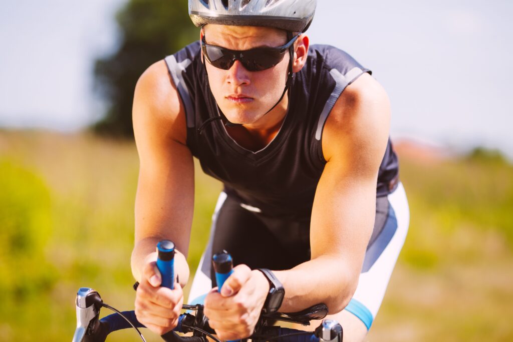 A triathlete who is not ready for a triathlon bike riding on their road bike with clip on aero bars