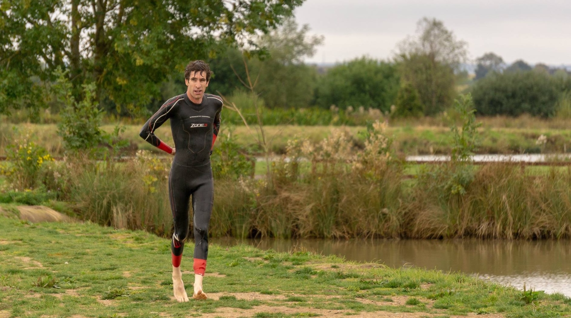 Triathlon Coach Simon Olney removing his wetsuit on his way to start the bike during a triathlon