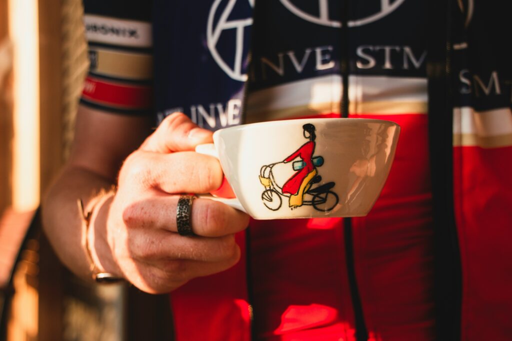 A cyclist holding a cup of coffee to get their dose of caffeine, an effective triathlon supplement