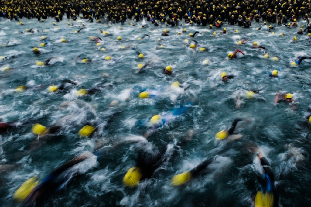 A huge group of swimmers taking to the water at the start of an IRONMAN event.
